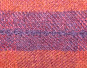section of purple with orange above and below, and mohair line of embrodiery across the purple.