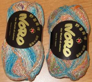 two balls of yarn in shades of turquoise, orange, and white.