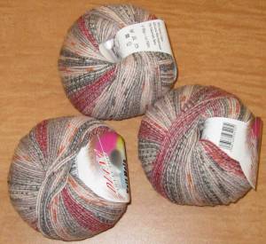 three balls of yarn in reds, grays, and pinks.